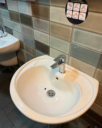 Seramik kaplı duvar önünde yeni takılmış beyaz lavabo ve tek kollu krom batarya